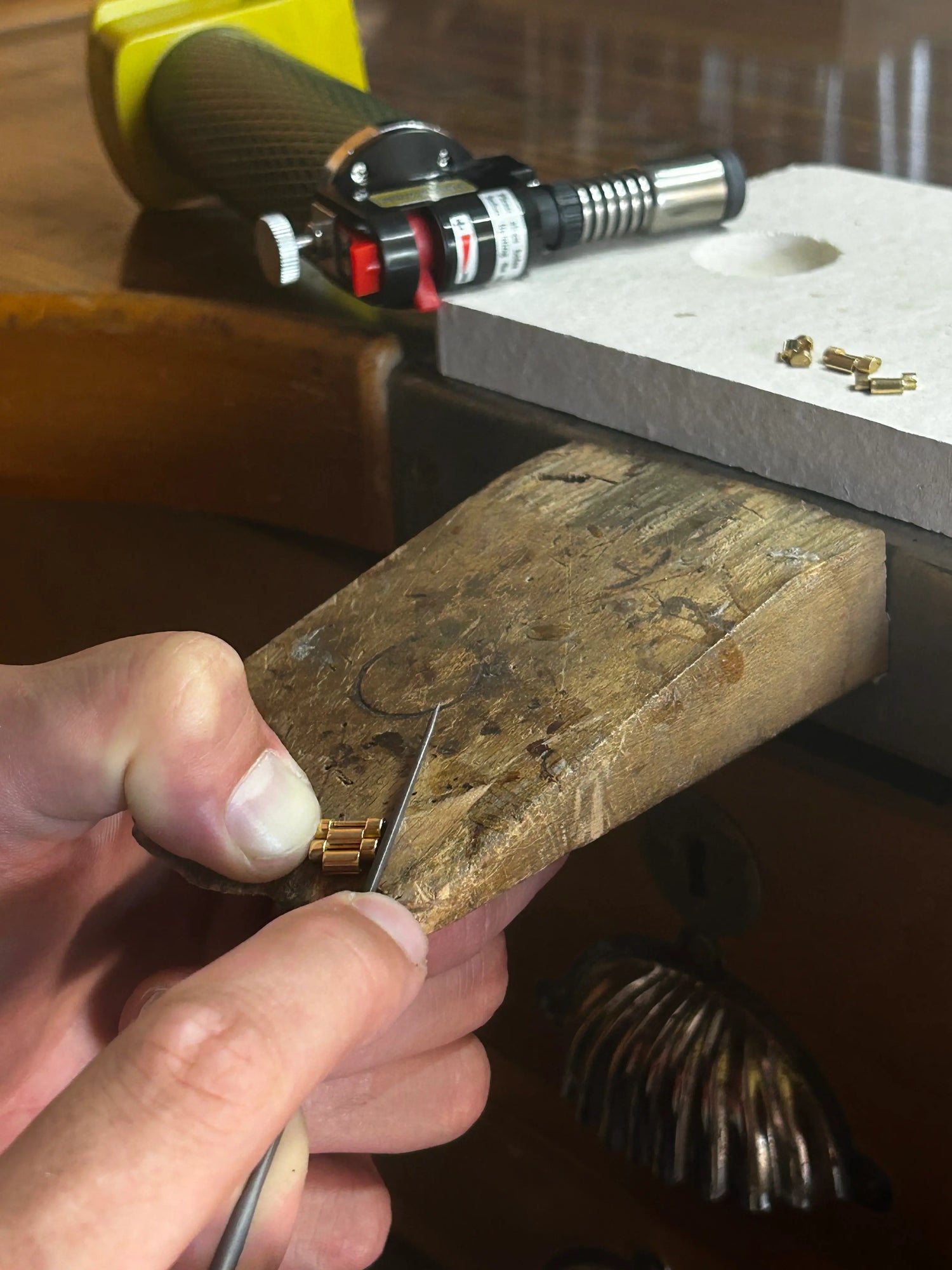 Filing the links of a gold watch bracelet.
